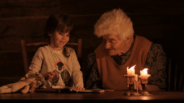 一个小女孩和奶奶在烛光下看书视频素材