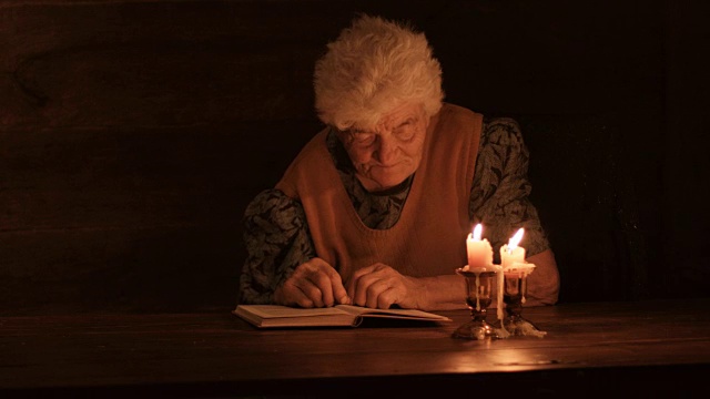 老妇人在烛光下看书视频素材