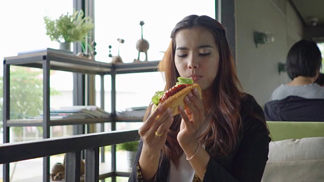 一个在咖啡厅吃三明治的快乐女人的肖像视频素材