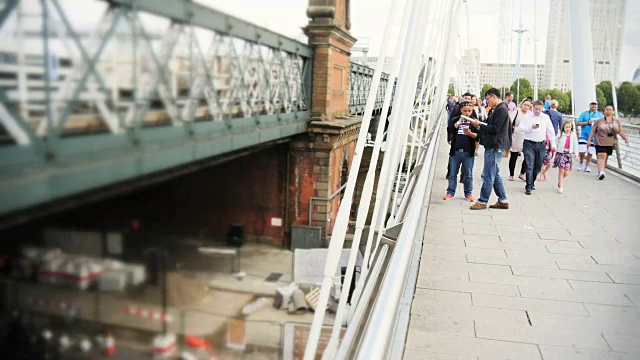人们在伦敦的金禧桥上穿梭，穿梭在火车和交通中视频素材