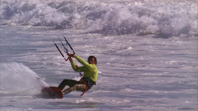 风筝冲浪者被举到空中，表演一个魔术，然后降落到水面上视频下载