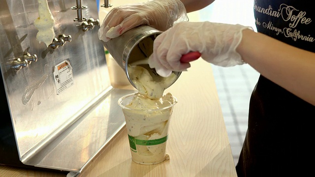 美国加州兰乔米拉市，工人戴着防护手套，将CU太妃香草奶昔倒入透明塑料盛杯，并盖上半圆形盖子视频下载