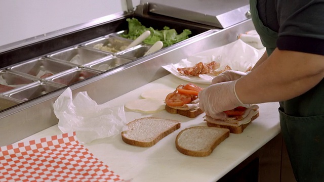 美国加州，屠呦呦熟食店的女店员正在制作培根生菜和西红柿三明治视频下载