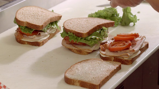 ECU三明治店砧板区，戴着防护手套的手准备培根、生菜和番茄三明治/ Cabazon，美国加州视频下载