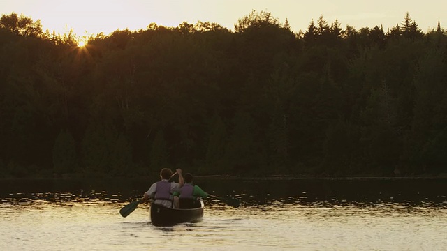 这是一对夫妇在美国缅因州的长池塘上划独木舟的照片视频下载