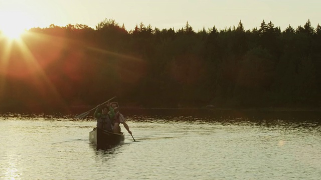 在美国缅因州的长湖上，一对夫妇在日落时划独木舟视频下载