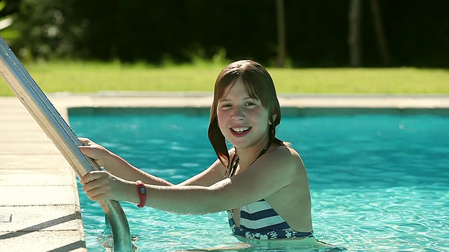 在西班牙马略卡Pollenca的游泳池里，女孩微笑着游泳视频素材