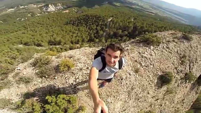 一个男人在悬崖顶上自拍视频。视频素材