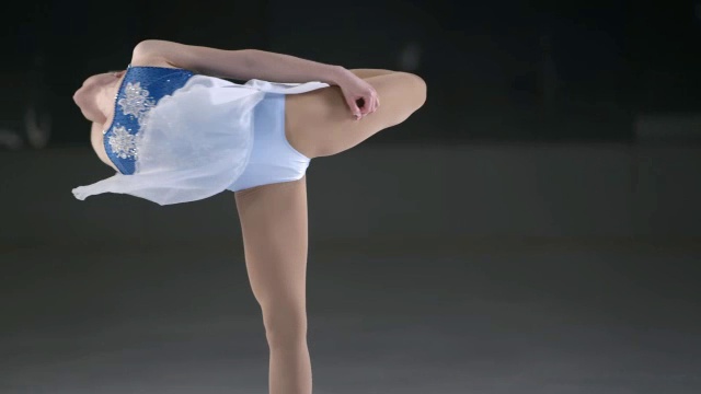 SLO MO女花样滑冰运动员在一个优雅的抓脚旋转视频素材