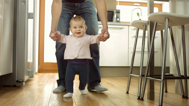 婴儿在父亲的帮助下迈出第一步视频素材