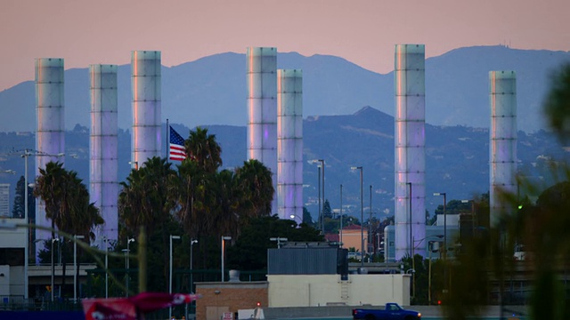 黄昏时分，一架飞机从前景和背景穿过，来到洛杉矶国际机场霓虹照明管的入口:湾流G-4和巴西航空工业公司crj视频素材