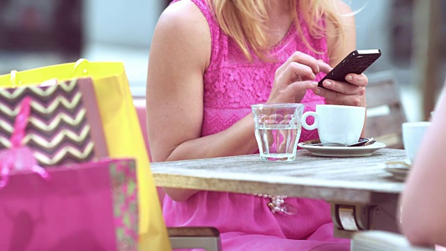 一个金发女人在和朋友喝咖啡的时候用手机视频素材