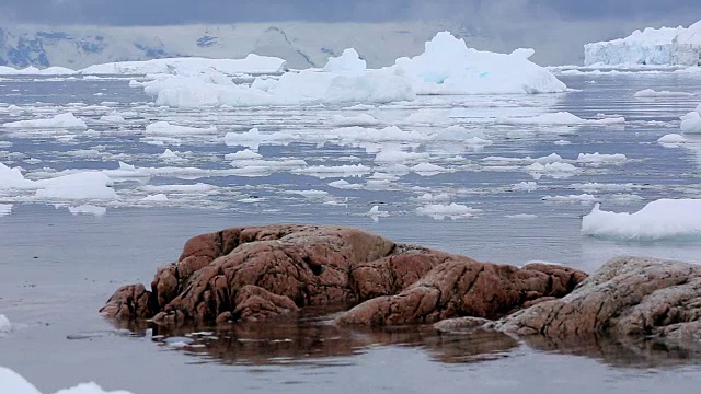 浮冰从露出地面的岩石上飘过视频素材