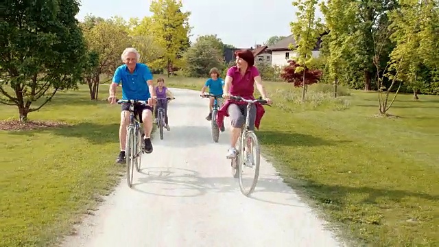 爷爷奶奶和孙子们骑着自行车穿过公园视频素材