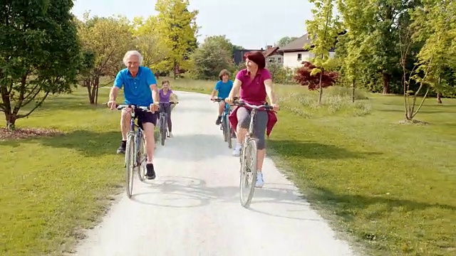 爷爷奶奶和孙辈们在一个阳光明媚的日子里骑着自行车视频素材