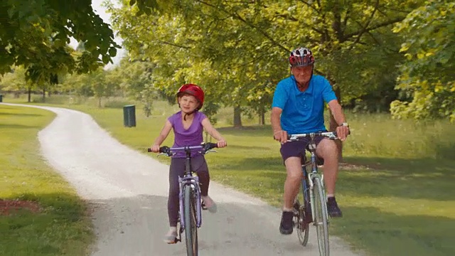 孙女和爷爷骑着自行车穿过公园视频素材