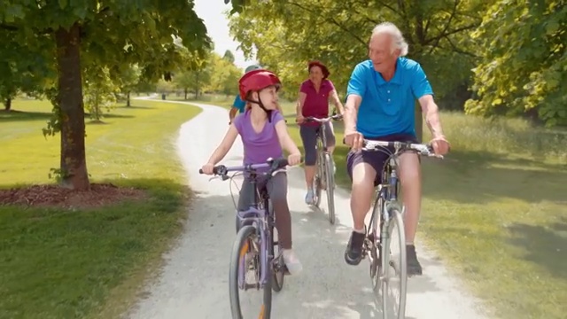 孙辈们和祖父母们骑着自行车穿过公园视频素材