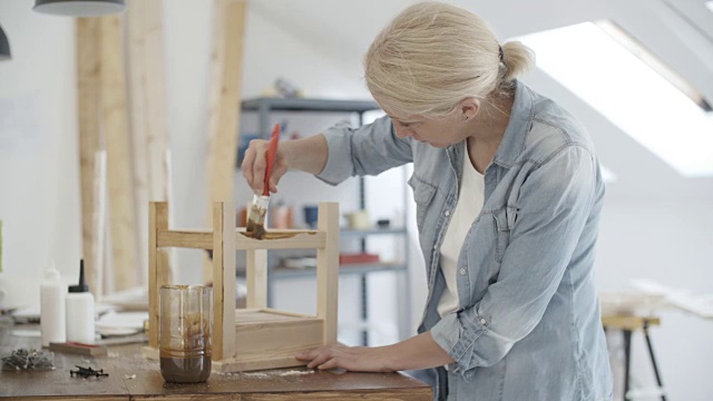 4K:木匠在她的工作室里画家具。视频下载