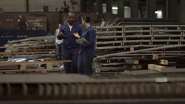 WS pan_在钢铁厂，同事们拿着平板电脑边走边聊视频素材