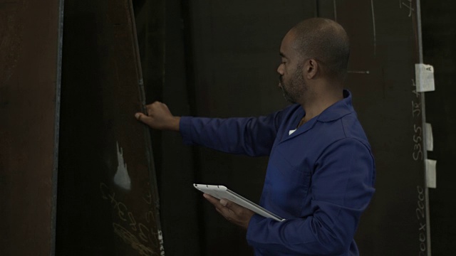 一名男性工人正在用平板电脑数钢板视频素材