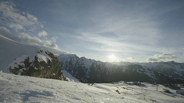 一名滑雪者越过镜头，从一个积雪覆盖的滑雪斜坡上跳下来。视频素材