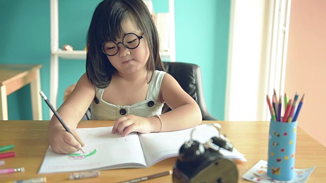 小女孩在桌子上看书和写书。视频素材