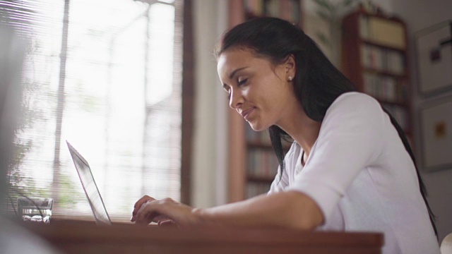 加州大学年轻女性在家用笔记本电脑工作。视频素材