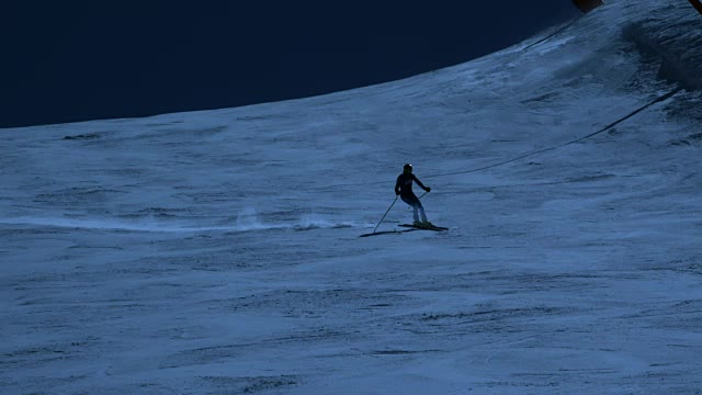 一名滑雪者在夜间滑下斜坡。视频素材