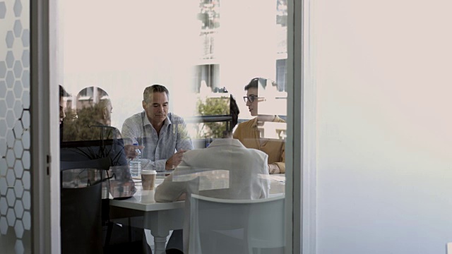 商务人士在玻璃幕墙的现代办公空间开会视频素材