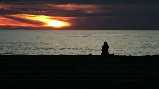 WS拍摄的女人坐在海滩上欣赏日落/洛杉矶，美国加利福尼亚视频素材