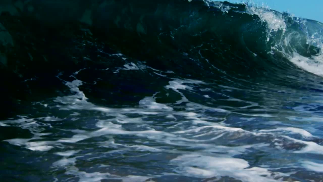 美丽的碰撞波POV波浪打破相机在加利福尼亚夏天的阳光浅沙滩上。慢动作在红龙上以300FPS的速度拍摄。视频素材