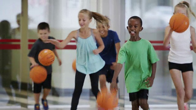 小学的孩子们在体育课上打篮球视频素材