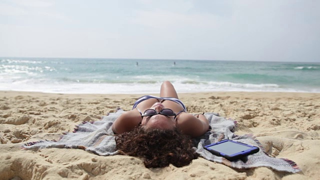 一名年轻女子在法国南部的海滩上晒日光浴。视频下载