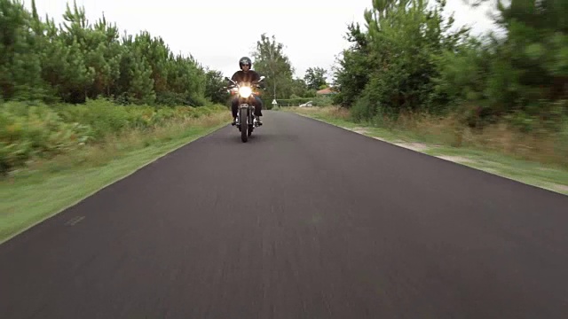 英俊的男子骑着摩托车在乡间小路上视频素材