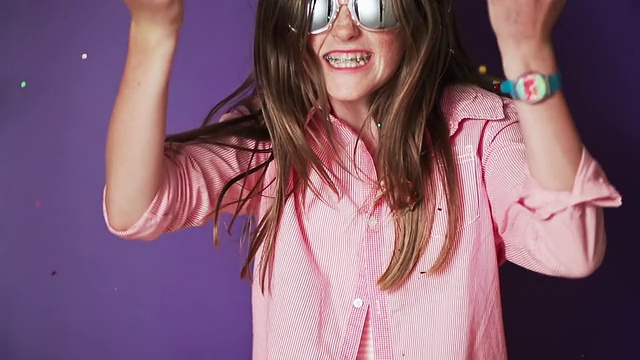 CU SLO MO年轻的女孩戴着太阳镜吹出五颜六色的闪闪发光，然后跳着舞和派对/新西兰奥克兰视频下载