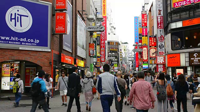 东京，日本人走在Shibuya车站附近的餐馆附近，在Shibuya十字路口有五颜六色的标志和拥挤的人群视频素材