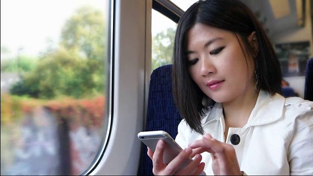 快乐的亚洲女人在火车上用手机。视频素材