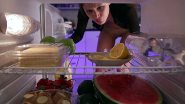 穿着内衣的女人从冰箱里拿出橙汁和苹果视频下载