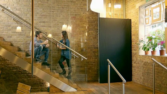 创意专业人士在现代办公空间的楼梯上聊天。视频素材
