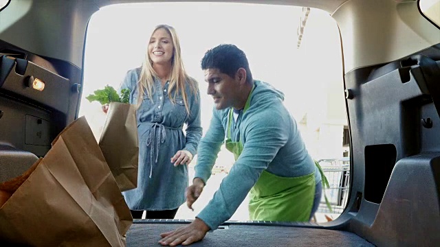西班牙裔杂货店员工正在帮妈妈和女儿把购物袋装进SUV或小货车视频下载
