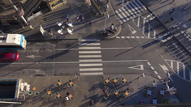 4K空中广角拍摄的人行横道。马德里这个十字路口的交通很流畅。行人过马路。我们可以看到下午侧面人影和车辆。还有酒吧餐厅露台的桌椅。视频素材