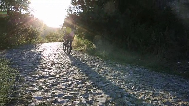 骑山地车的人爬上鹅卵石小路，日出视频素材