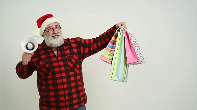 老人显示拷贝空间和礼物在圣诞老人的帽子在一个灰色的背景视频下载