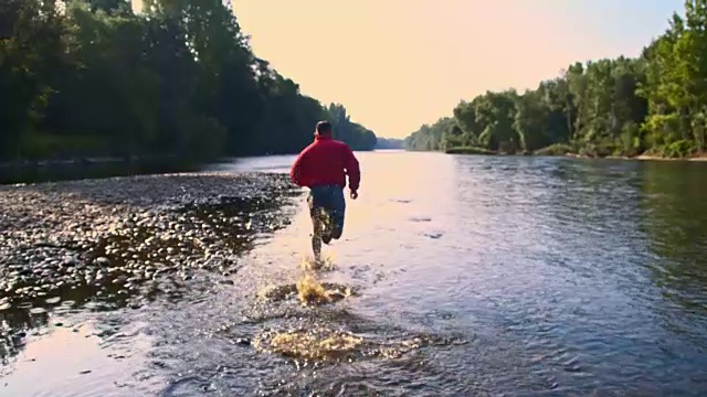 SLO MO跑步者在一条浅河里溅起水花视频素材