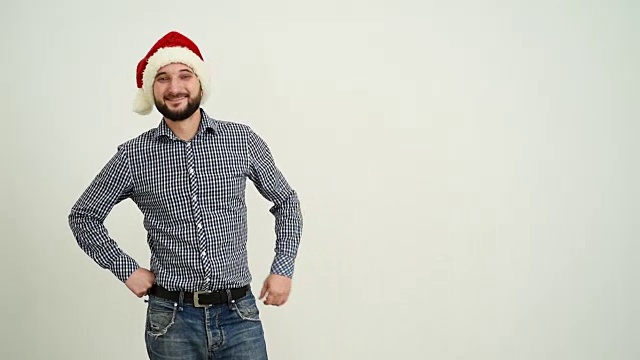 年轻的成年男子在灰色的背景上展示一顶帽子里的圣诞老人的拷贝空间视频下载