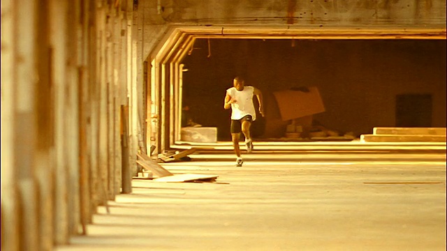 SEPIA慢镜头长镜头黑人男运动员跑向建筑物水泥地面上的摄像机视频下载