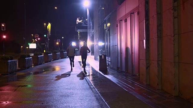两个女性朋友在城市的雨夜跑步视频素材