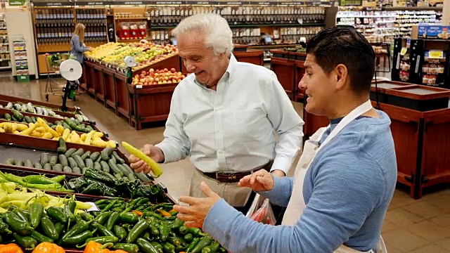 西班牙裔超市员工正在和高级白人男性顾客谈论辣椒品种视频素材