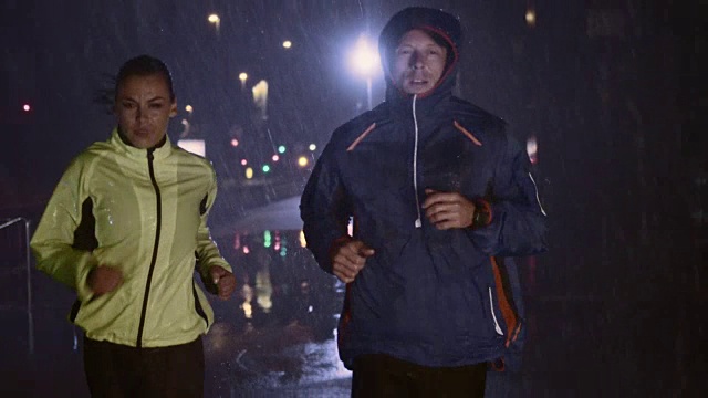 SLO MO TS夫妇晚上在城市街道上跑步视频素材