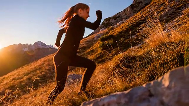 年轻的女性跑步者在日落时跑上了山视频素材